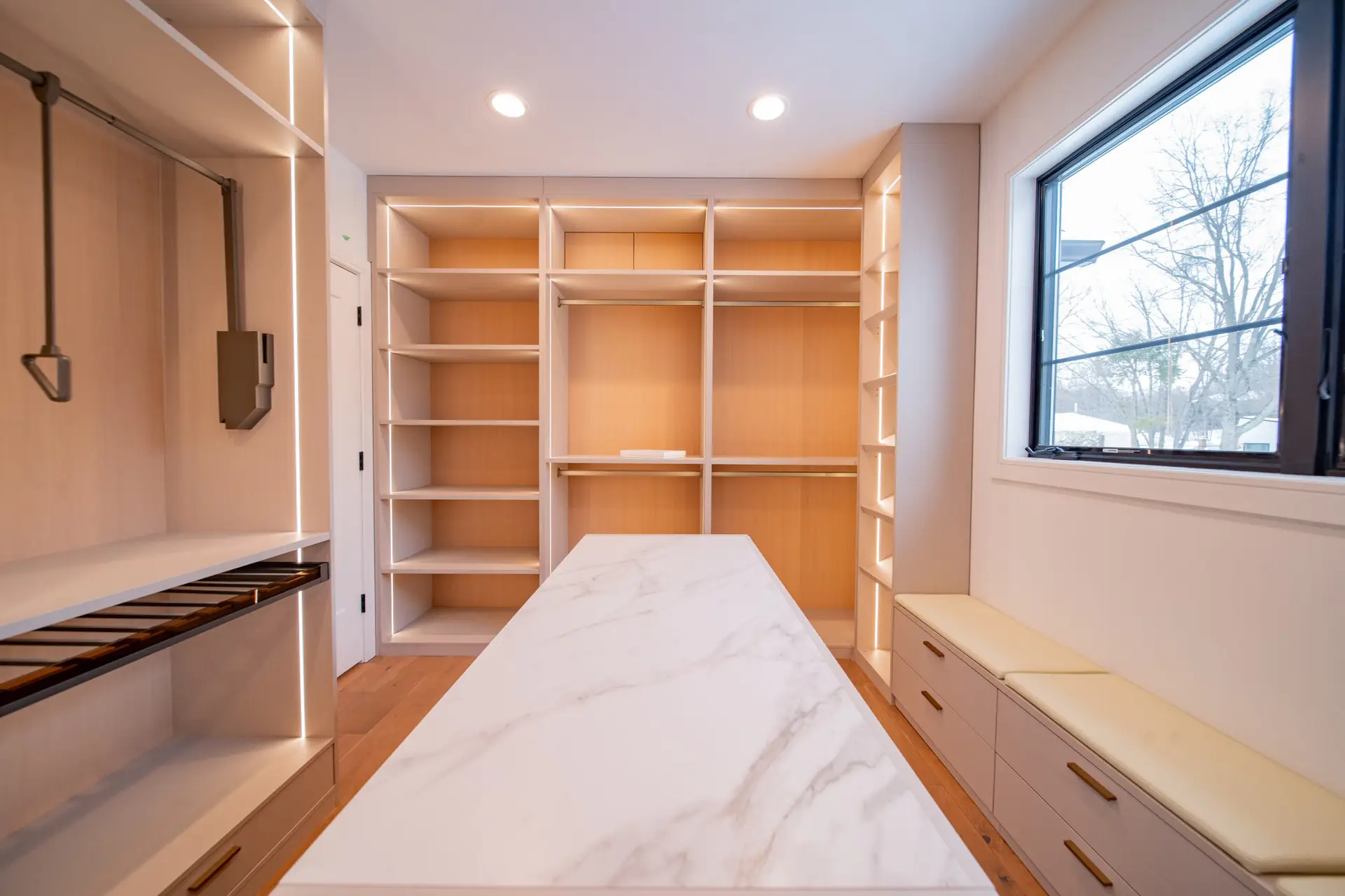 Custom walk-in closet island with white stone countertop in a luxury made-in-America closet design