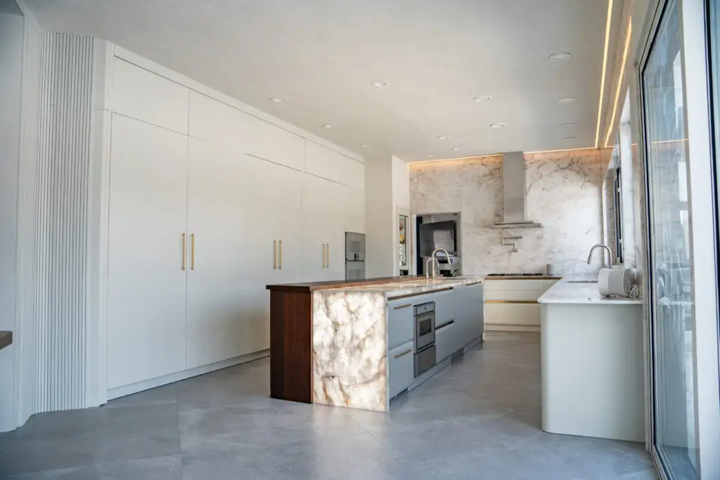 Front angle view of a minimalist custom kitchen with tall cabinets and quartzite finishes by Americana Studio