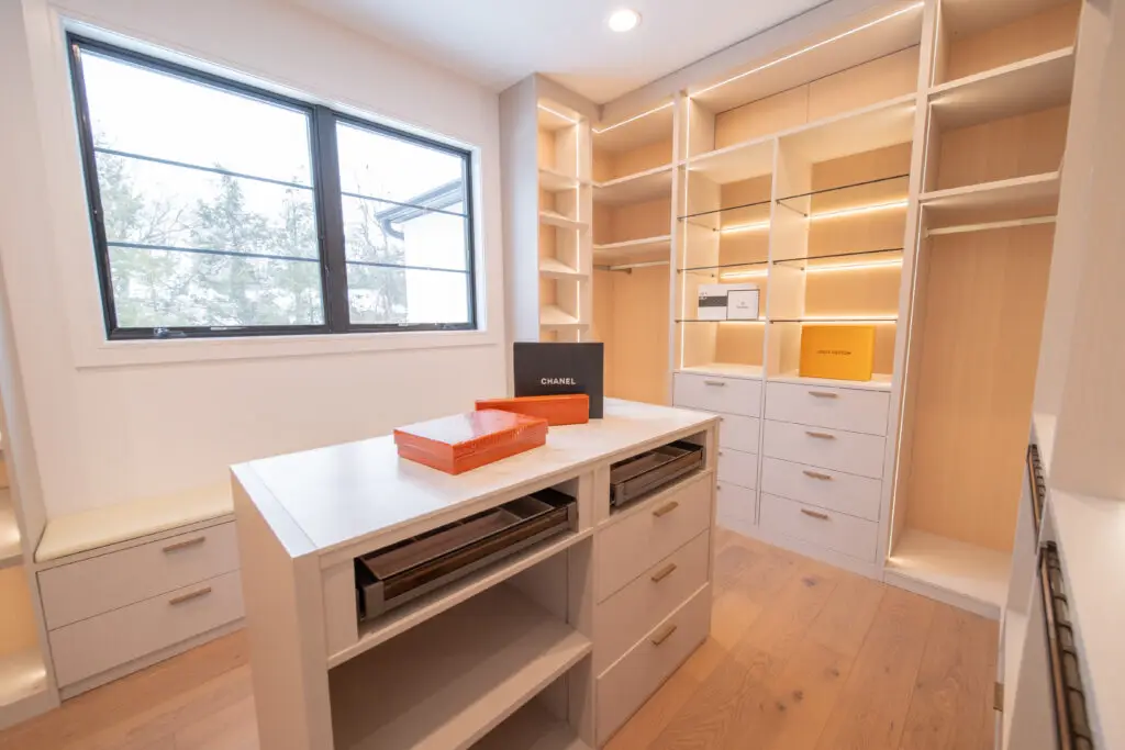 Unfinished walk-in closet before custom cabinet installation with drywall, temporary hanging light, and exposed room layout